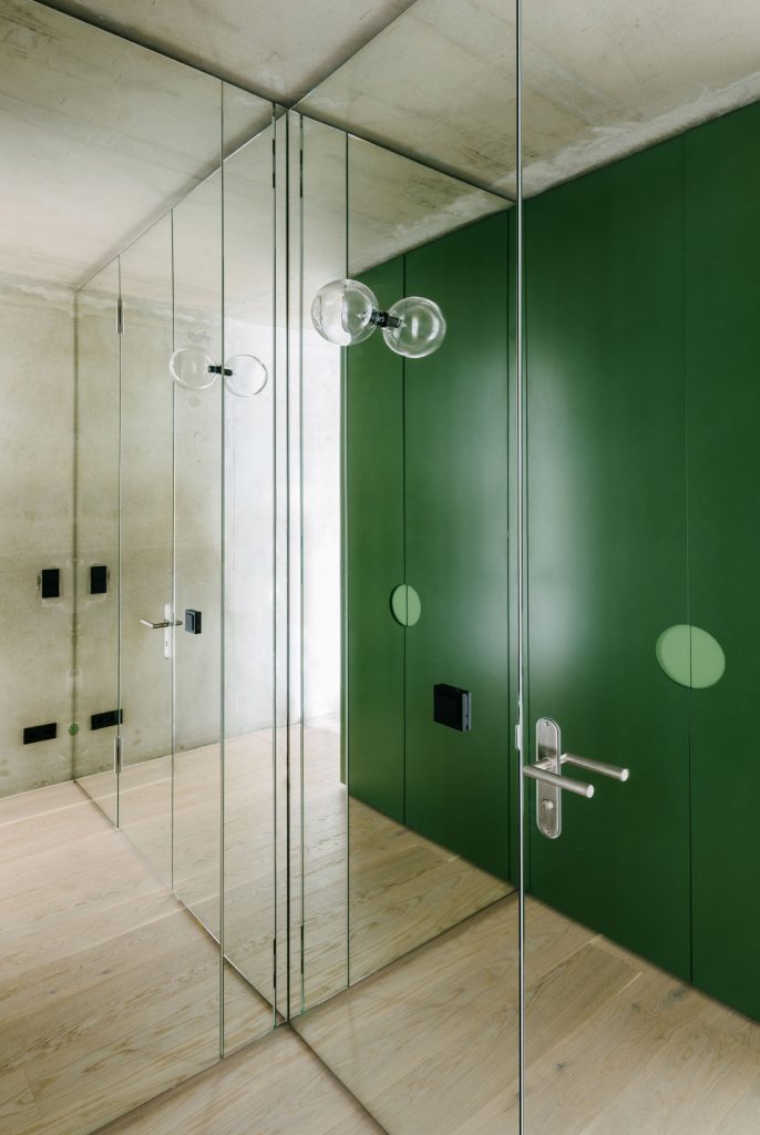 Walls of mirrored glass playfully reflect the green box and the exposed concrete shell, Photos ©Robert Rieger, Courtesy of Ester Bruzkus Architekten.