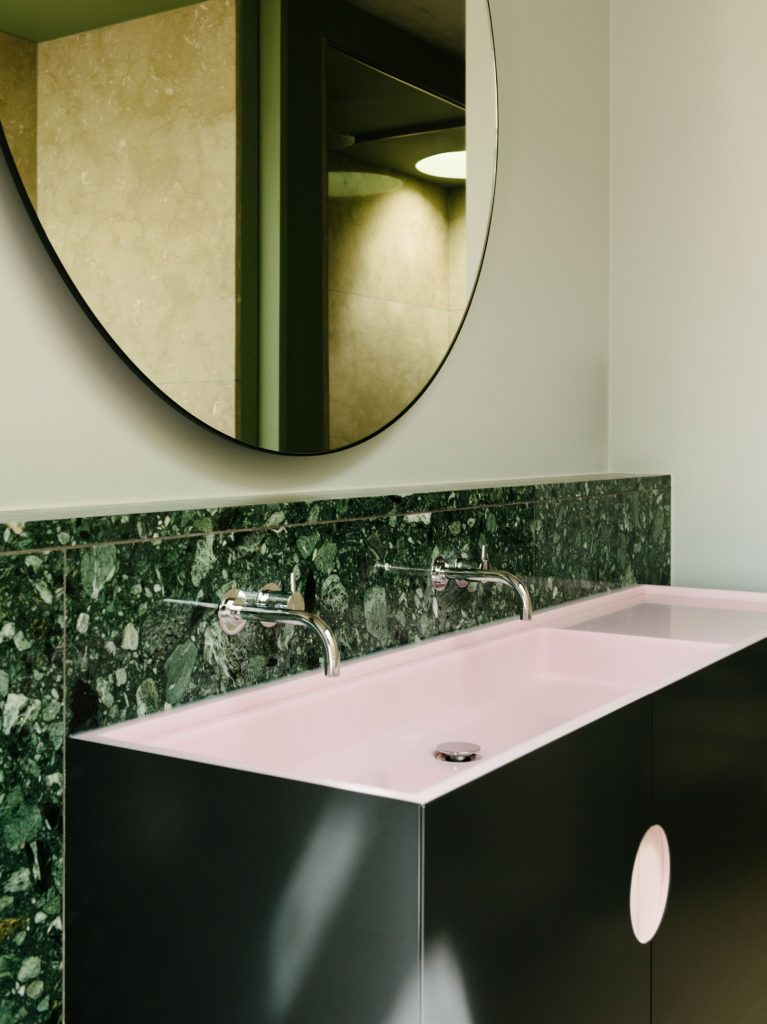 The bathroom sinks are made from green marble, black steel door fronts and pink CORIAN basins.