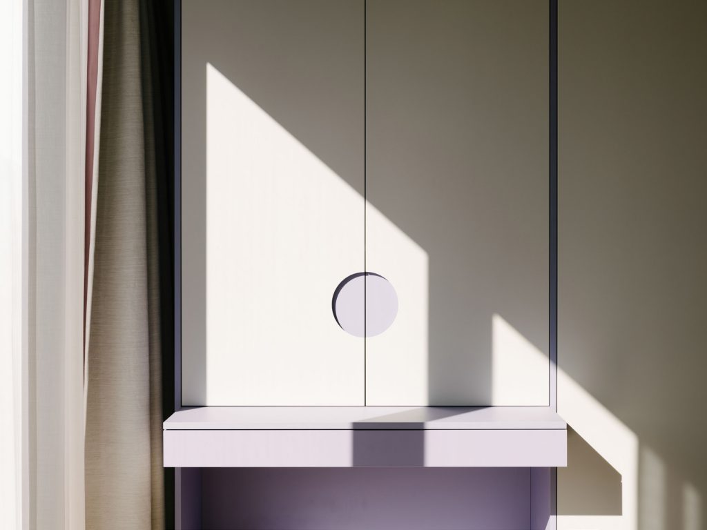 BEDROOM - A violet and gray desk that is built into the cabinetry. The large circle is the handle to the cabinet that recalls a similar detail in the bathroom. Photo ©Robert Rieger, Courtesy of Ester Bruzkus Architekten.