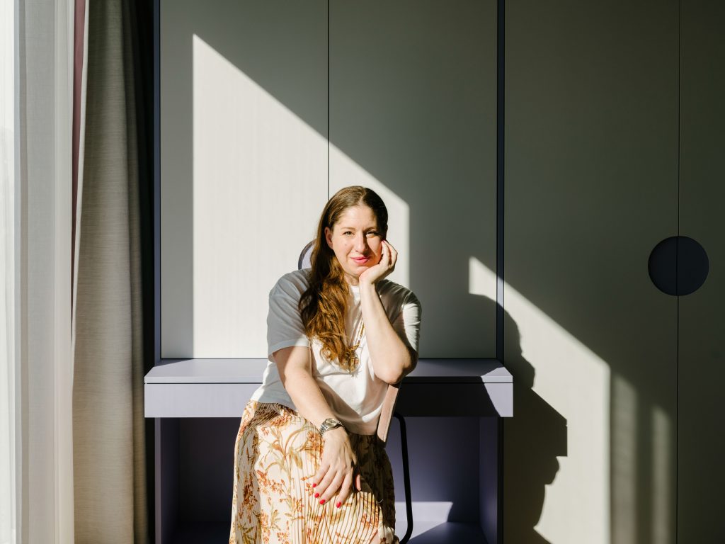 Ester Bruzkus poses at the violet table in the Green Box. Photo ©Robert Rieger, Courtesy of Ester Bruzkus Architekten.