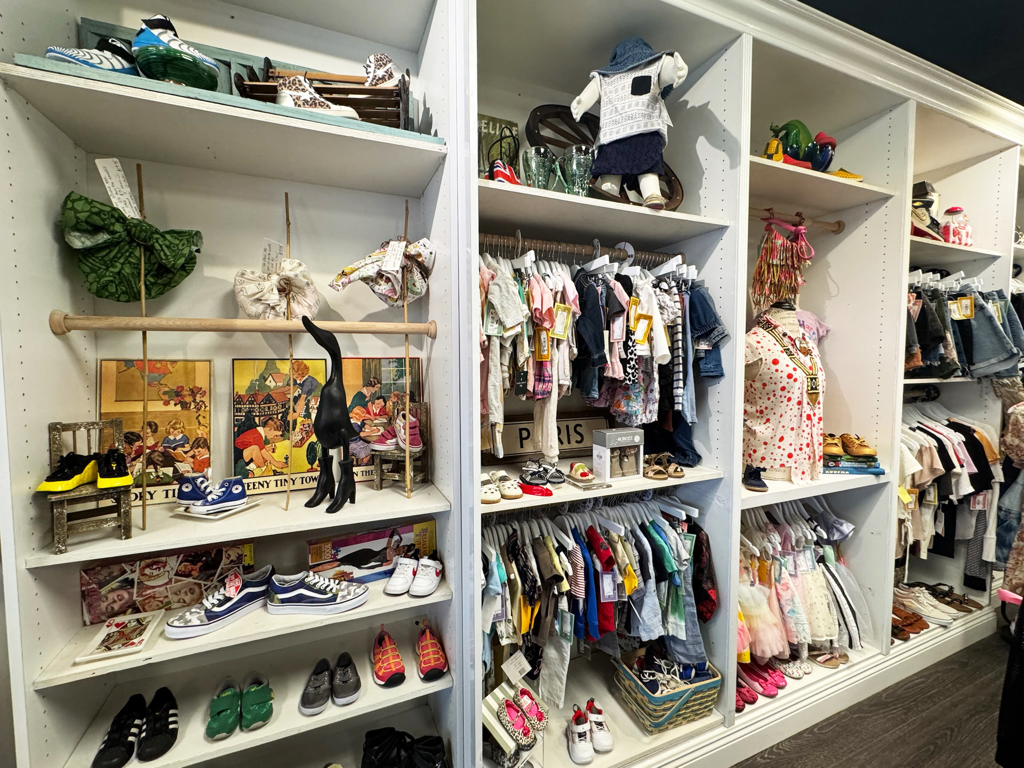 Kids' shoes and accessories displayed alongside storybook decor, reinforcing Project ReWear's family-focused, community-first values. Photo courtesy of Project ReWear.