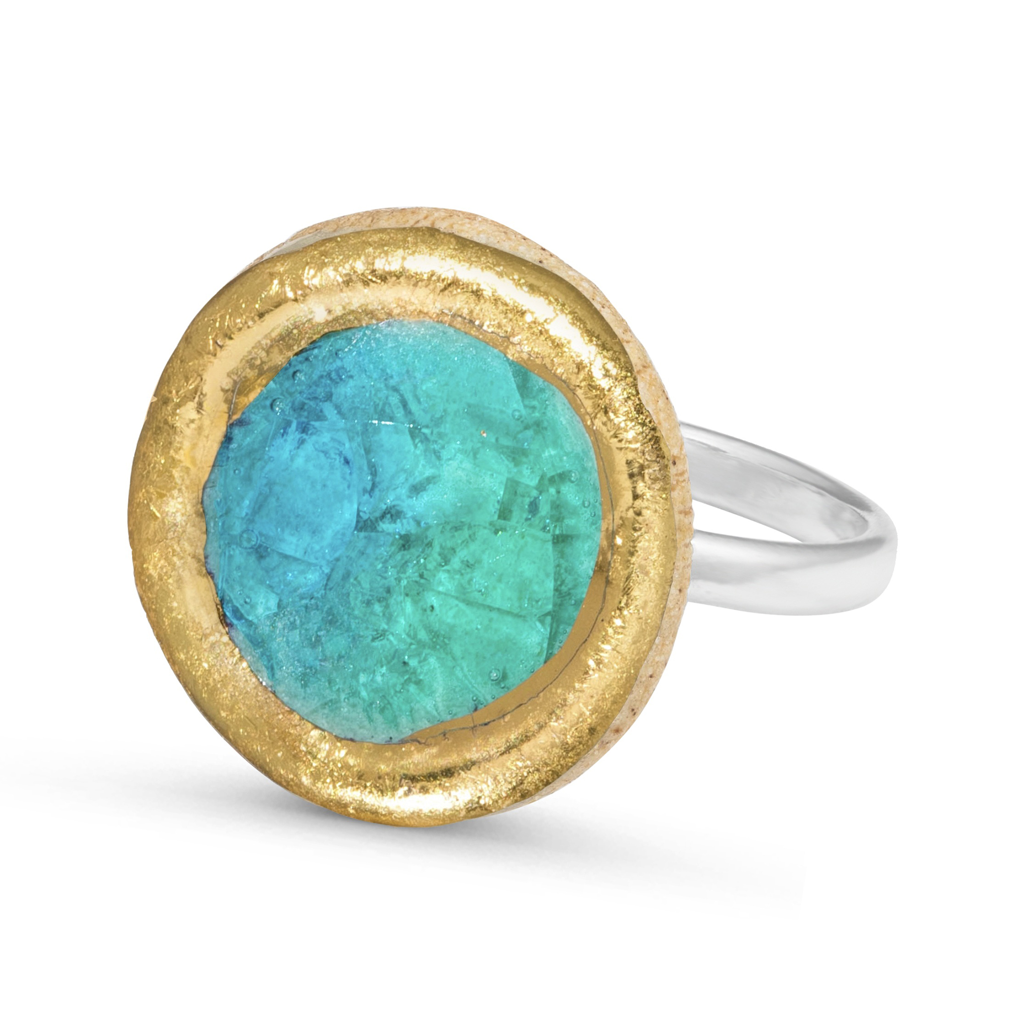 Turquoise Blue Lagoon Statement Ring The Turquoise Blue Lagoon statement ring is handcrafted from ceramic and glass, and finished with real gold detailing, the ring is set on an adjustable sterling silver band. Each piece is individually shaped and painted, ensuring every ring is completely unique. The kiln-fired glass creates a smooth, gemstone-like surface with a subtle tactile quality. Natural variations in color and form are to be expected. Over time, the outer edge of the gold detailing may gently fade, revealing the ceramic beneath. Care instructions should be followed to preserve the finish. Approximate dimensions: 2 cm diameter. The adjustable band can be widened to size P or reduced to size L; when widened, a small gap may appear at the band.